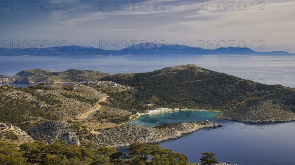 View of a coastal landscape with hilly vegetation and blue water, Holy Week, Bay of Panormitis, Panormitis Monastery, Symi, Dodecanese, Greek Islands, Greece