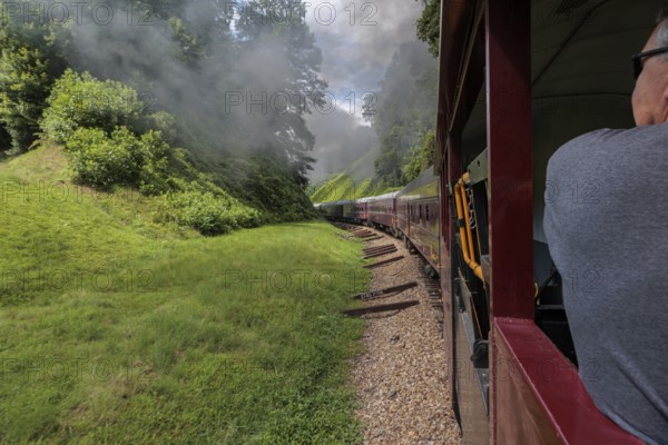 Steam from the Great Smoky Mountains Railroad hangs in the air as the train rounds a curve through the mountains of North Carolina