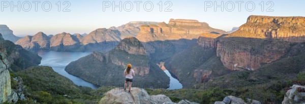 Hiker enjoying sunset at Blyde River Canyon with Three Rondawels peak, view of canyon with Blyde River and table mountains in the evening light, Canyon landscape, Panorama Route, Mpumalanga, South Africa