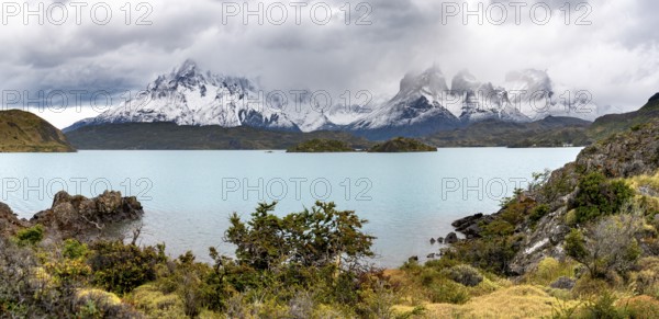 Cloudy mountain range Cuernos del Paine, shore of the blue lake Lago Pehoe in the evening light, dramatic sky, Torres del Paine National Park, Chile
