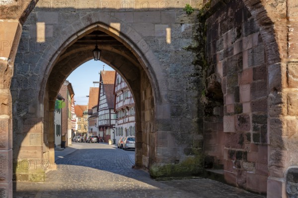Alley with cobblestones leads through the town gate Oberes Tor, view through the gate to the half-timbered houses of the old town in the evening light, Wolframs-Eschenbach, Middle Franconia, Bavaria, Germany