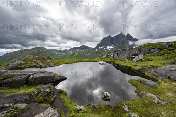 Small lake in mountain landscape, hike to Barden mountain, Breidtind mountain peak behind, Senja, Norway
