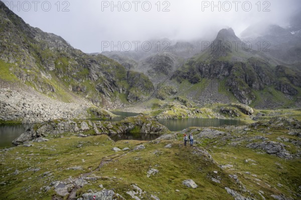 Two female mountaineers in a cloudy mountain landscape, Kreuzsee mountain lake, Wiener Höhenweg, Schober group, Hohe Tauern National Park, Carinthia, Austria