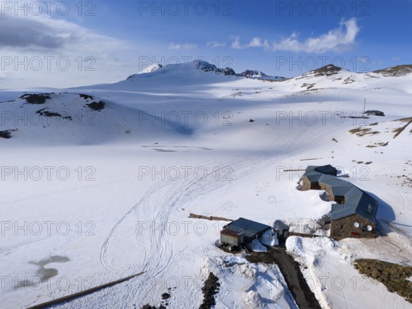 Snow-covered huts lie in a peaceful mountain landscape under a blue sky, aerial view, Aragaz, Aragac, Alagyaz, extinct stratovolcano, 4090 m, Aragazotn, Shirak, Armenia