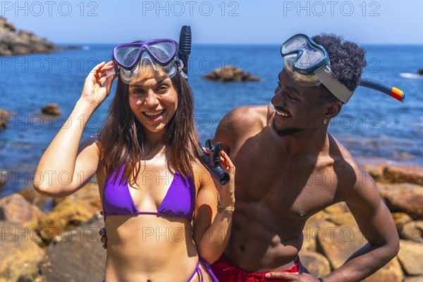 Young couple smiling and wearing snorkeling masks at the beach, eagerly preparing for an exciting snorkeling adventure in the ocean