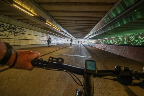 Ride your bike through the tunnel under the tracks of Utrecht Central, HBF, on the central cycle path on the Lange Viestraat, Vredenburg, in the city centre of Utrecht, lanes for pedestrians, cyclists and public transport vehicles are separated, dense cycle traffic, Netherlands