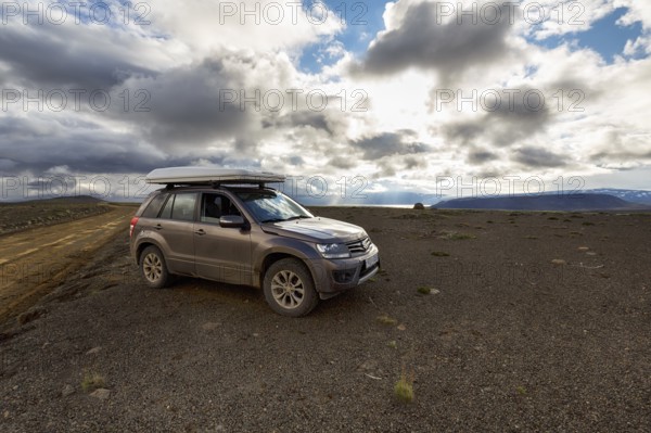 SUV, SUV with roof tent parked next to gravel road F35, Kjalvegur Kjölur, barren stony volcanic landscape, plateau, dramatic cloudy sky, Icelandic highlands, Suðurland, Sudurland, Iceland