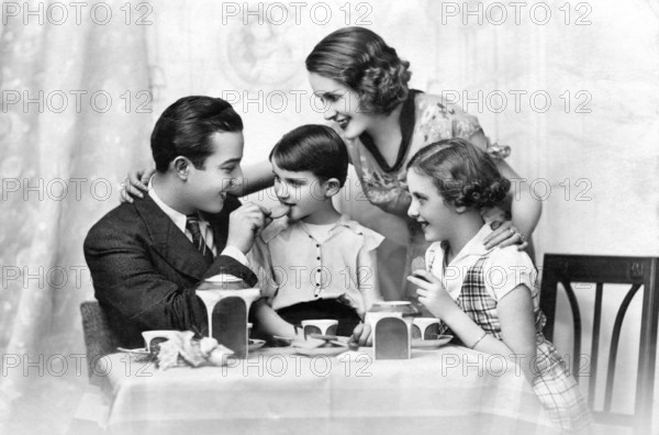 Family at breakfast, 1930s, Happy family at the table, laughing together and enjoying tea time, Historical photo