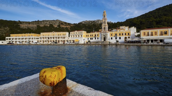 View over the harbour to the monastery with a striking tower and yellow buildings, Holy Week, Bay of Panormitis, Panormitis Monastery, Symi, Dodecanese, Greek Islands, Greece