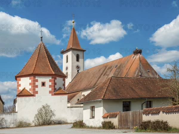 Church of the Visitation of the Virgin Mary in the village of Rauenzell in spring, storks and stork nests on the roofs, Herrieden, Middle Franconia, Bavaria, Germany