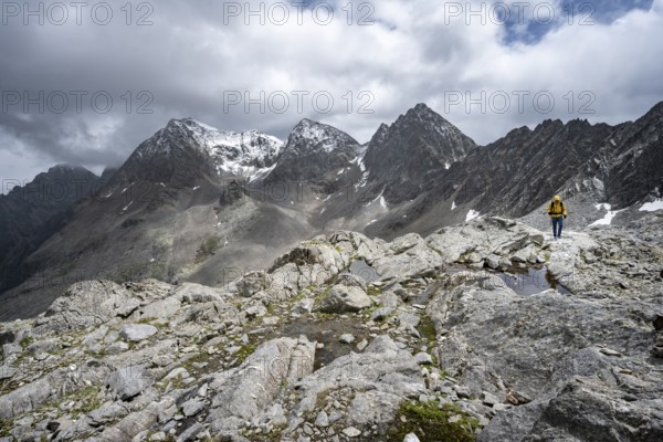 Mountaineer, Small mountain lakes in rocky mountain landscape, Niedere Gradenscharte, summit of Petzeck in the background, Schober group, Hohe Tauern National Park, Carinthia, Austria