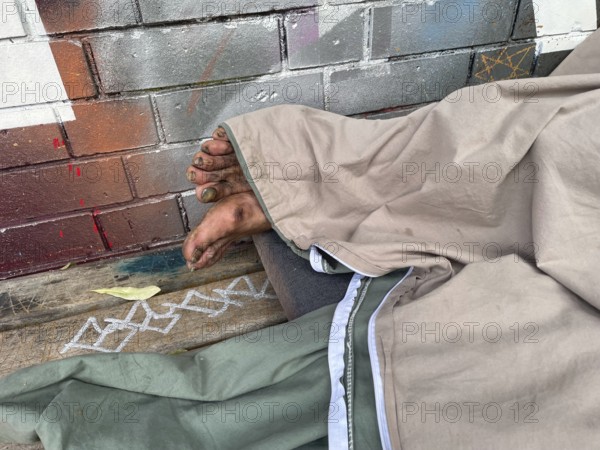 Homeless man sleeping on a bench, Yorkstrasse corner Möckernstrasse, Friedrichshain-Kreuzberg district, social issue, poverty, homelessness