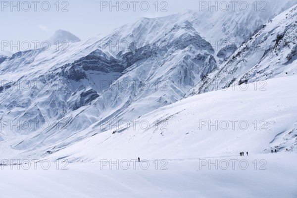 People walking through the snow, in the high mountains, Himalayas, Spitital, Kaza, Himachal Pradesh, India