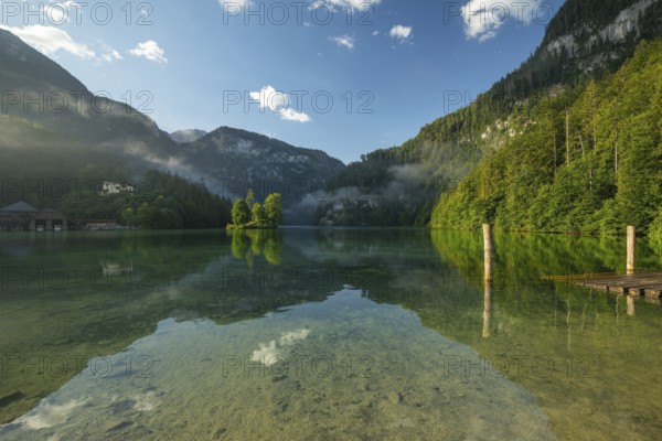 Mystical morning at Königssee in Schönau with boathouses and Christlieger. Sunrise and beautiful wafts of mist over the Königssee in the basin