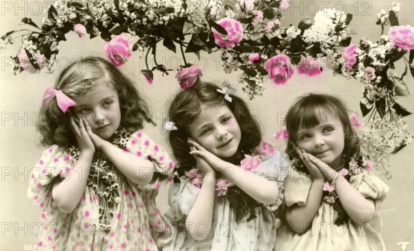 3 girls with flowers, 1900, Three girls in old-fashioned clothes with flowers and pink decorations, Historical photo