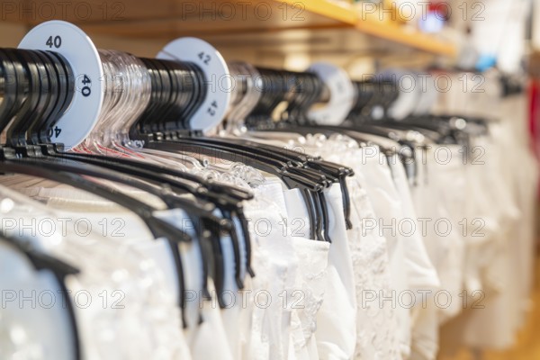 White shirts on hangers with size labels in a shop, focus on the size display, Sindelfingen, Germany