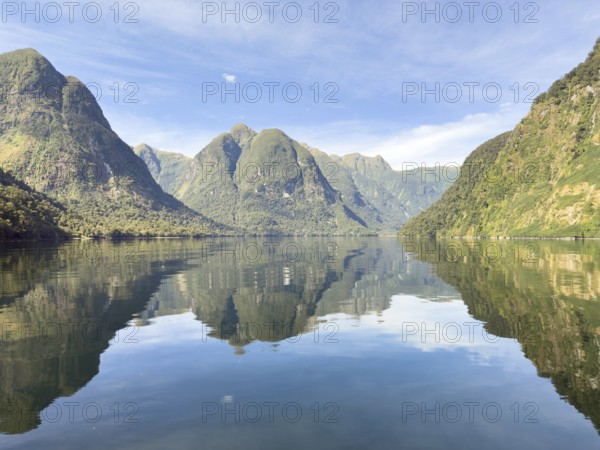 Mountains with reflections in the water against a blue sky in Doubtful Sound, South Island, New Zealand, Oceania