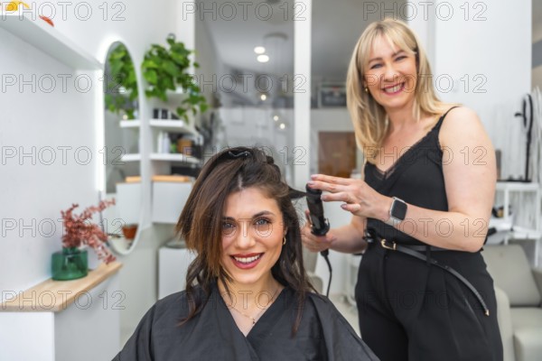 Smiling hairdresser styling hair of female customer with a curling iron in a modern, vibrant hair salon filled with beauty and fashion