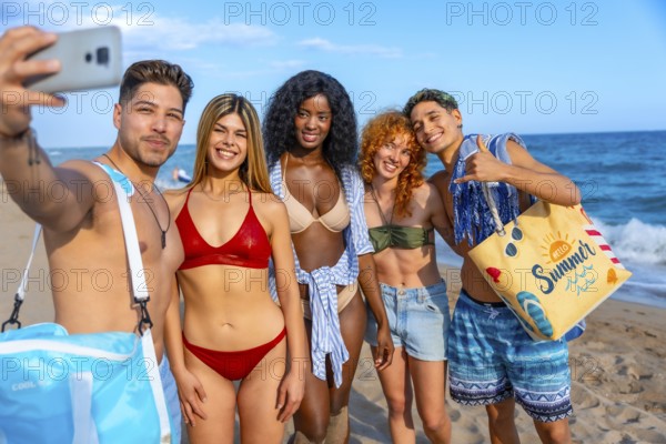 Group of cheerful young multi ethnic friends in swimwear taking selfie on the beach during summer vacation