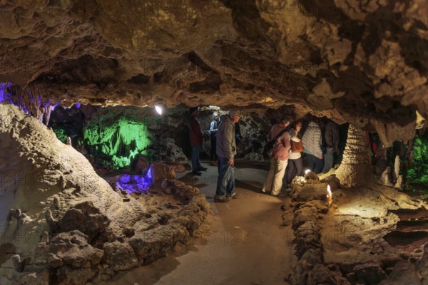 Tourists walking past limestone rock formations in a cave at Florida Caverns State Park in the Florida panhandle near Marianna