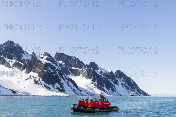 Zodiac in front of mountain range with snow, sea, Fugelfjorden, Spitsbergen, Svalbard