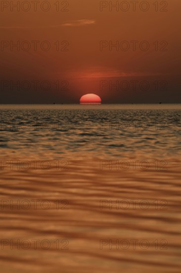 When the red sun sinks into the sea... Cuxhaven, North Sea, sunset in calm weather, glowing red fireball, sun sets fiery red over the sea, sinks into the sea, atmospheric picture, local nature, Lower Saxony Wadden Sea National Park, North Sea near Cuxhaven, Duhnen, Lower Saxony, Germany, Western Europe