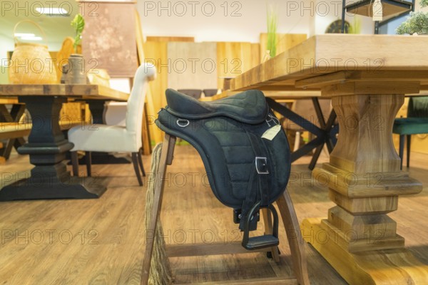 A saddle lies on a wooden chair in a furniture shop, surrounded by rustic woodwork, Sindelfingen, Germany