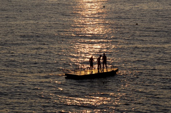 Children playing on bathing island, bathing raft, swimming island, Étretat, sea, sunset, evening mood, Normandy, Seine-Maritime, France