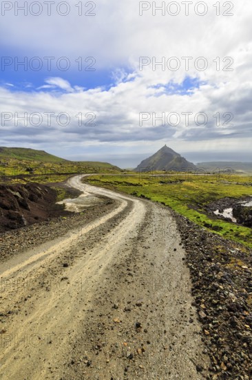 Gravel track through barren moss-covered volcanic landscape, cone-shaped mountain Stapafell, rain clouds, changeable weather, Arnarstapi, Snaefellsjökull volcanic system, Snaefellsnes peninsula, West Iceland, Iceland