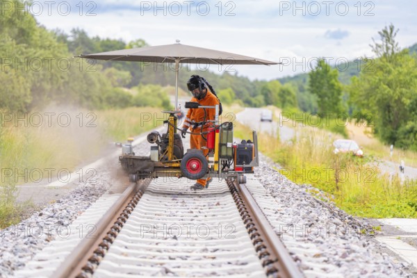 A worker carries out welding work with machines on a railway track, grinding work on the Hermann Hesse railway, Ostelsheim, district of Calw, Germany