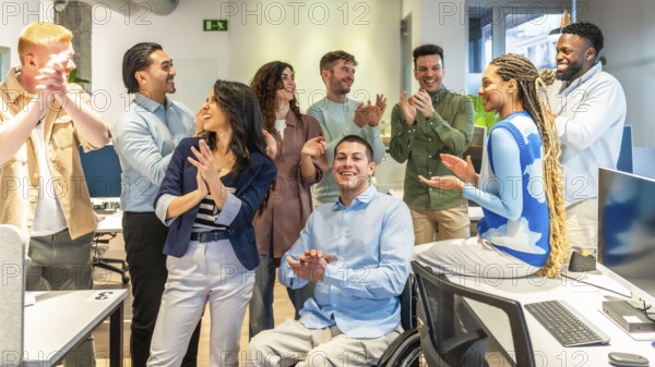 Happy business team celebrating success, clapping and congratulating a colleague in a wheelchair