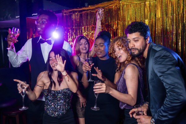 Group of cheerful elegant friends having fun together and drinking sparkling wine while dancing and celebrating at nightclub