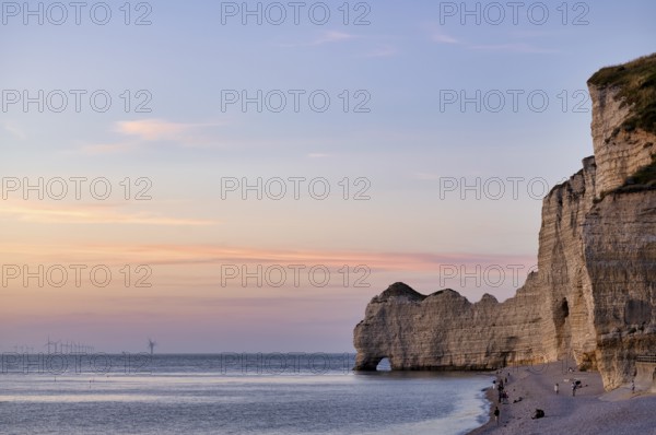 People on the beach, pebble beach, rock arch Falaise or Porte d'Amont, Étretat, sea, steep coast, cliffs, chalk cliffs, alabaster coast, La Côte d'Albâtre, evening mood, atmospheric, Normandy, Seine-Maritime, France