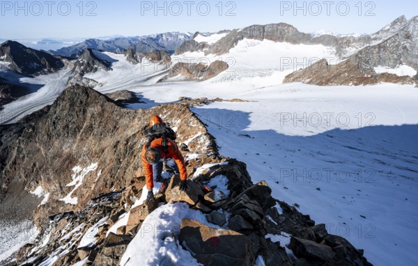 Mountaineer climbing on a rocky ridge on the mountain peak Wilder Freiger, in the background Signal summit and summit of Becher with Becherhaus, picturesque high mountain landscape, view of glacier Übeltalferner and rocky mountain peaks Königshofspitz and Sonklarspitze, Stubai Alps, South Tyrol, Italy