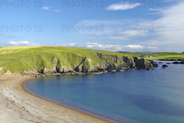 Green hills hug a sandy coastline with calm blue waters and wide open skies, Hillswick, Eshaness, Shetland Islands, Scotland, United Kingdom