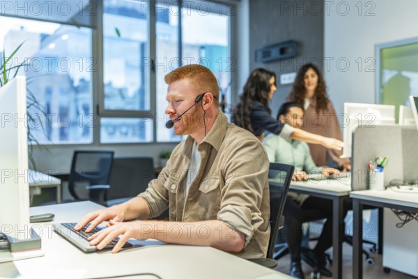 Focused call center agent providing customer support, typing on keyboard while wearing headset in bustling office environment
