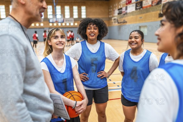 Happy multi ethnic female basketball players listening to coach instructions during training in a gymnasium