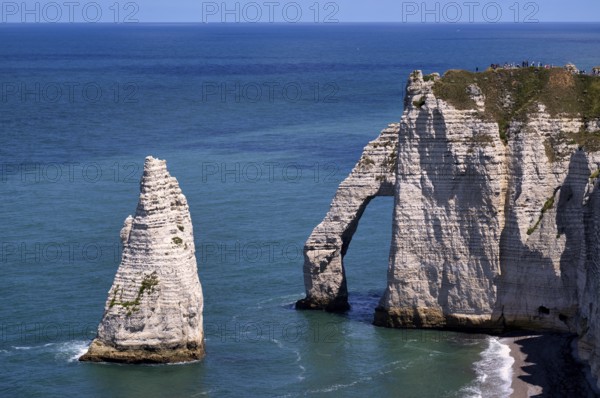 Tourists, visitors on rock arch Falaise or Porte d'Aval and rock needle Aiguille, Étretat, sea, steep coast, cliffs, chalk cliffs, alabaster coast, La Côte d'Albâtre, Normandy, Seine-Maritime, France