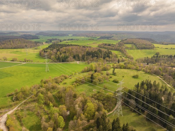 Wide fields crossed by power lines under a cloudy sky, Glems reservoir, Swabian Alb, Germany