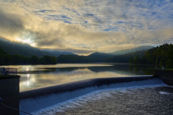 Sunrise over a reservoir, Paulushof dam, dam with flowing water, cloudy sky and mountains, summer, Rursee, Obersee, Rurberg, Simmerath, Eifel National Park, North Rhine-Westphalia, Germany