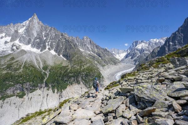 Picturesque mountain landscape of imposing mountain peaks and glaciers, mountaineer on hiking trail, Grand Balcon Nord, glacier tongue Mer de Glace, behind Grandes Jorasses, Mont Blanc massif, Montenvers, Chamonix, Haute-Savoie, France