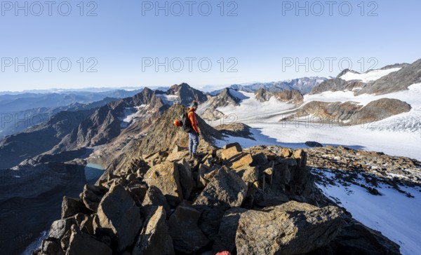 Mountaineer on a rocky ridge, ascent to the Wilder Freiger, behind the summit of the Becher with Becherhaus, picturesque high mountain landscape, view of the Übeltalferner glacier and rocky mountain peaks, Stubai Alps, South Tyrol, Italy