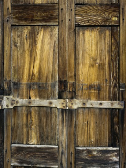 Close-up view reveals a weathered wooden door adorned with intricate patterns and robust metal accents, capturing the essence of rustic charm in a historic location