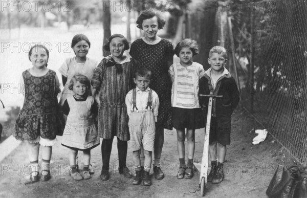 Boys and girls on the pavement, 1920s, group of children posing laughing on a rural road, historical photo
