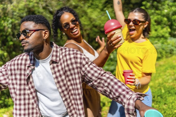 Three friends enjoying summer sunshine, dancing joyfully while sipping cold drinks and sharing laughter in a vibrant outdoor setting