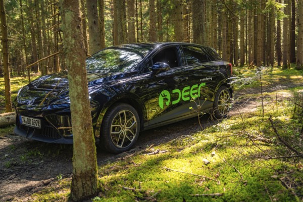 Black car on a forest path, surrounded by tall trees and sunlight, Deer E- Carsharing, Calw, Black Forest, Germany