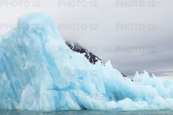 Iceberg in front of mountain, blue glacier ice, Smeerenburgbreen, Scandinavia, Spitsbergen