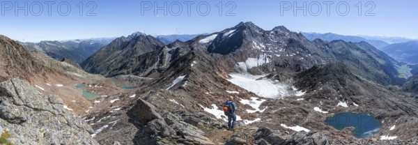 Mountain panorama, mountaineer in rocky high mountain landscape at the Rotgratscharte, view of mountain landscape with blue glacier lake, descent from the summit Roter Grat, Stubai Alps, South Tyrol, Italy