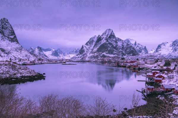 Fishermen's Village in front of snowy mountain range at the coastline in winter, Lofoten, Norway
