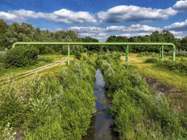 Bottrop, North Rhine-Westphalia, Germany - Renaturalised Boye, the tributary of the Emscher, has been transformed into a near-natural watercourse, flood protection through newly designed flooding areas, the Boye is now free of wastewater following the construction of a parallel sewer, is part of the Emscher river system and thus part of the Emscher conversion, was previously an open, above-ground wastewater channel, mixed water channel with surface water and wastewater. Wind turbine on the Mottbruch spoil tip at the back